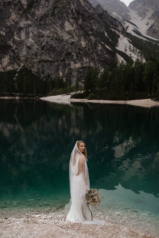 Bride holding dried bouquet at Lago di Braies in the Dolomites in Italy during elopement wedding Ana Galloway Photography