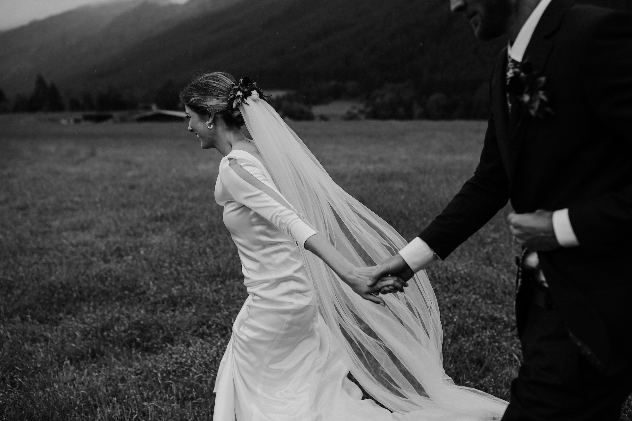 Bride and Groom smiling and running in a field with the veil flying Queenstown Elopement Ana Galloway Photographya