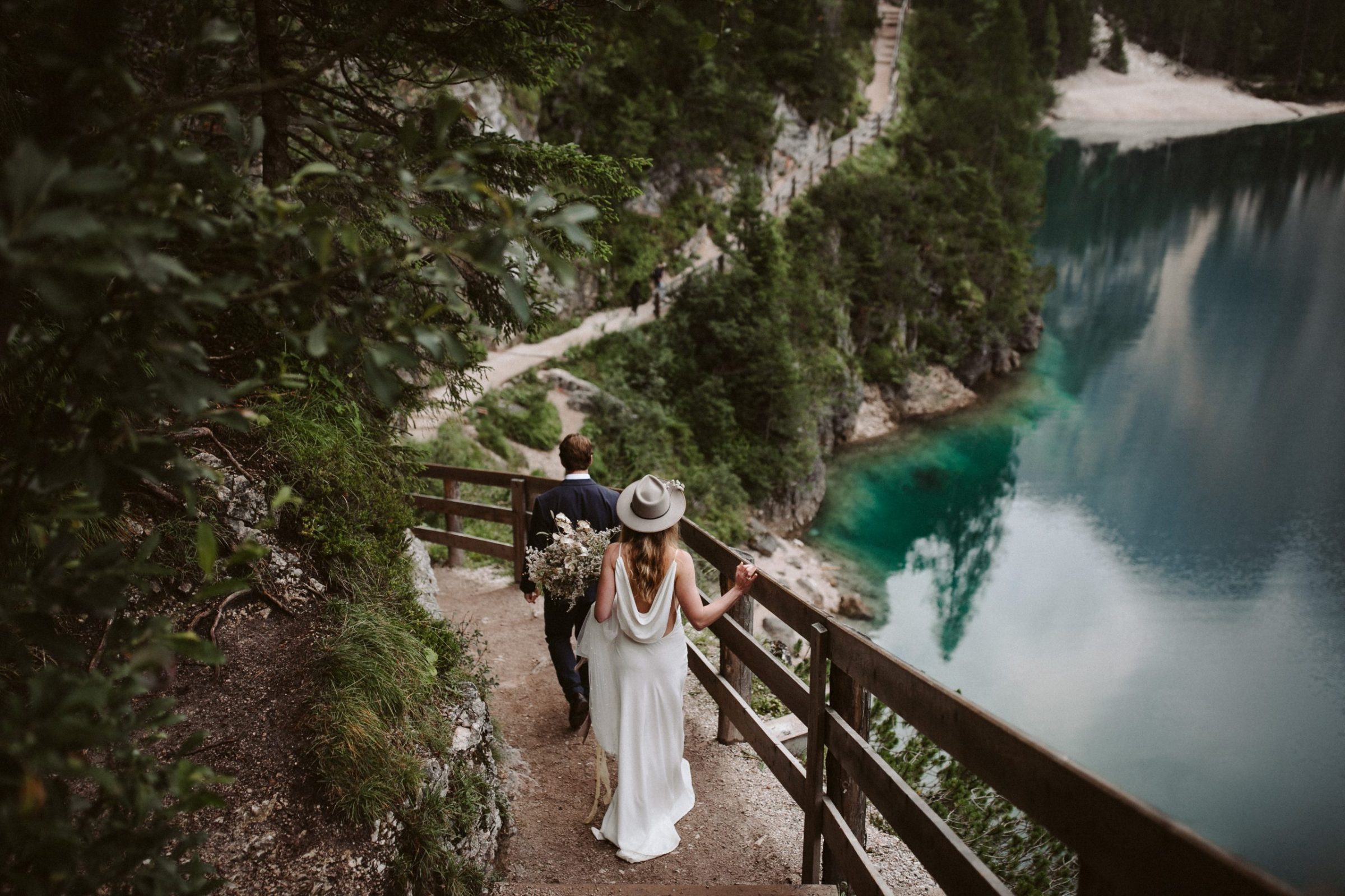 Bride and Groom walking along track at Lago di Braies in the Dolomites in Italy during their elopement wedding Ana Galloway Photography