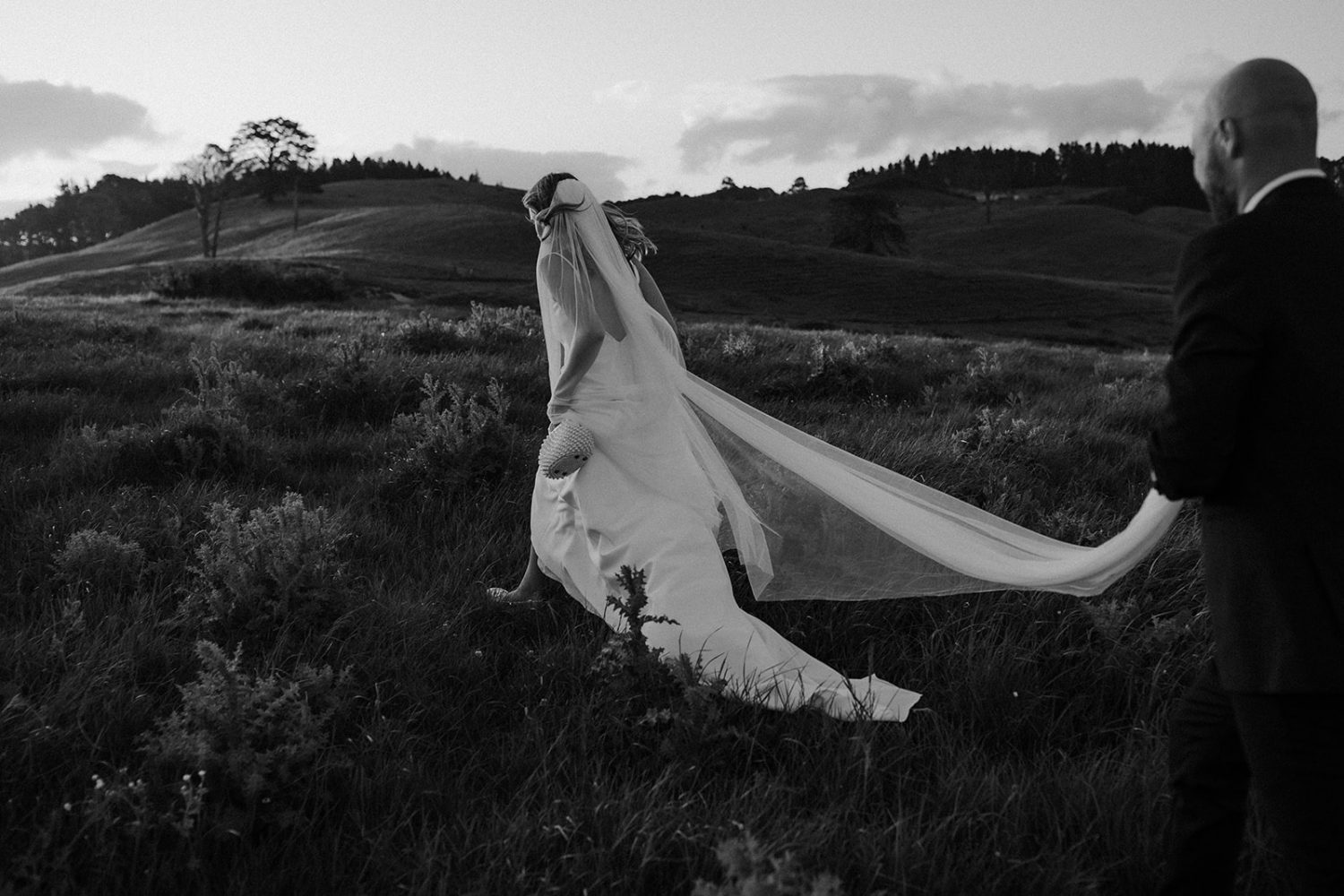 bride and groom walking in the middle of beautiful mountains in Wainui, Auckland black and white Ana Galloway Photography