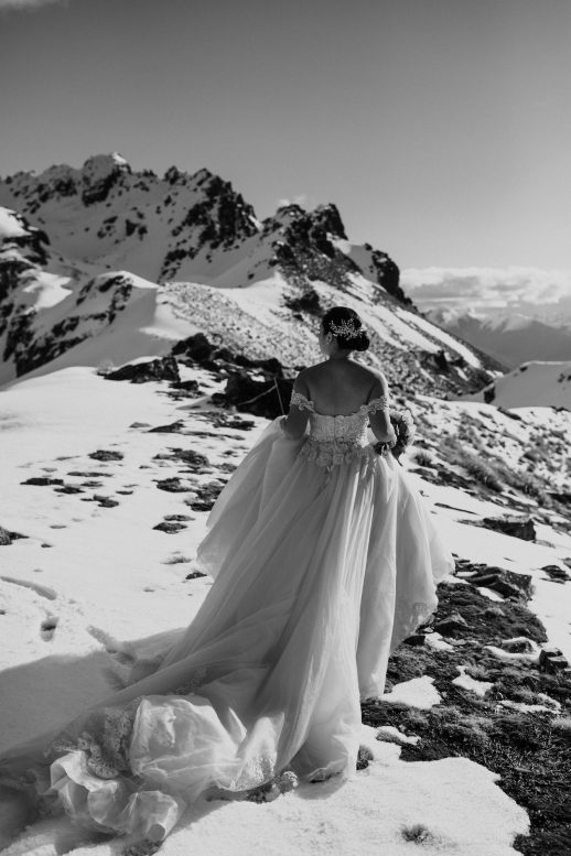 Bride in her lace and tulle bridal gown on top of a snowy mountain in the midst of winter Queenstown Wedding Ana Galloway Photography