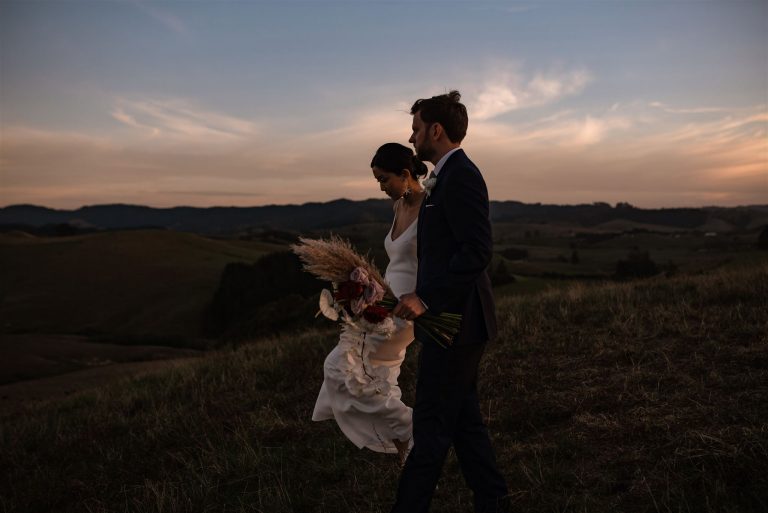 Bride and groom walking through the mountain of Kauri Bay Boomrock with a sunset view Ana Galloway Photography