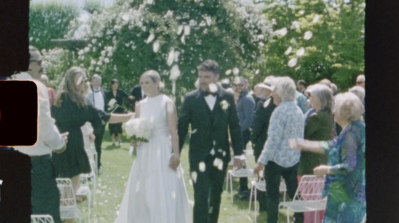 modern bride and groom walking down the aisle with white rose petals thrown over them frame from super 8 film Ana Galloway Photography