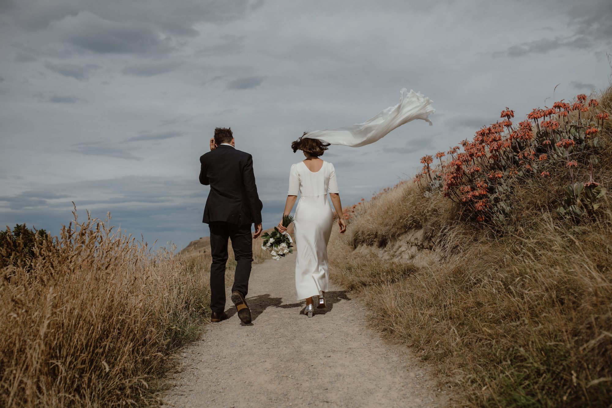 Bride and Groom walking pass on the grassy mountain and cold breeze Ana Galloway Photography