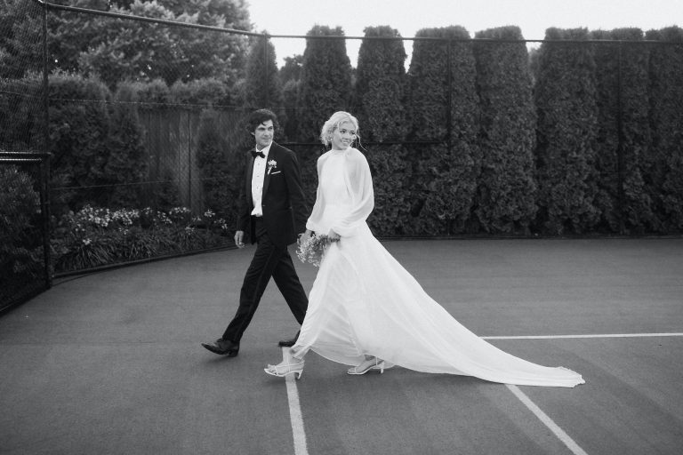 Elegant bride and groom walking across tennis court Ana Galloway Photography