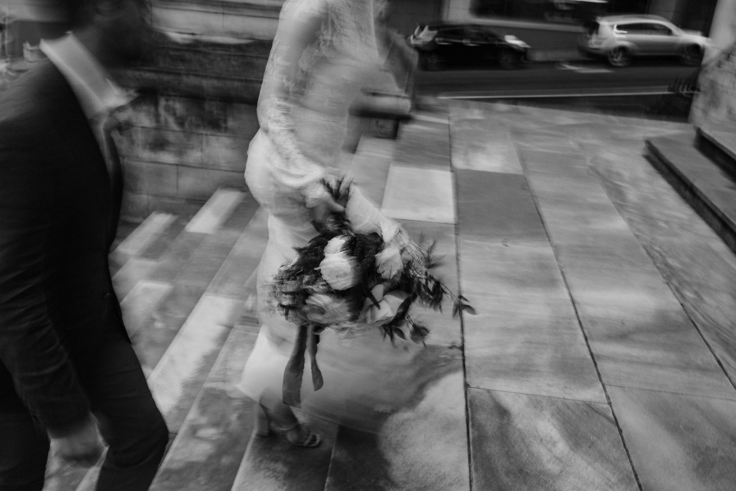 Black and White blurred picture of bride and groom walking up the cathedral steps Dunedin Wedding Ana Galloway Photography